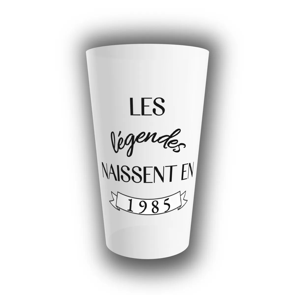 Gobelet réutilisable personnalisé anniversaire avec le texte Les légendes naissent en 1985 inscrit en noir sur un fond translucide